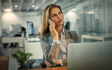 Just calling to say Ill be working late. Shot of a businesswoman talking on her phone during a late shift at work.