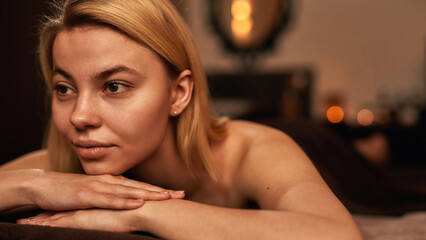 Obraz na płótnie Canvas Woman rest on massage table and think in spa salon