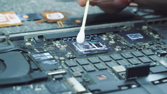 Technician in hardware service cleans the CPU or gpu from the old thermal paste to apply a new one