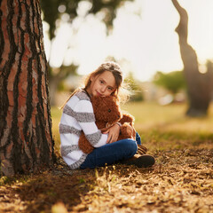 Sometimes all you need is a hug from your bear. Portrait of a sweet little girl hugging her teddy bear while playing outside.