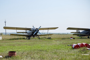 Fototapeta na wymiar An old Soviet-era plane stands on a field airfield among barrels of fuel