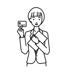 立って書類とカードを手に持つビジネススーツの女性