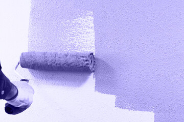 rasit hand wall paint using a paint roller while working indoors