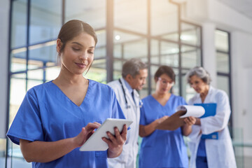 Theyre making some groundbreaking medical discoveries. Cropped shot of a medical practitioner looking at a patients file on a digital tablet with colleagues in the background. - Powered by Adobe