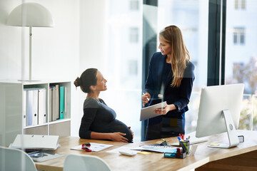This office is positively glowing. Shot of a pregnant businesswoman and a colleague using a digital tablet together in an office. - Powered by Adobe