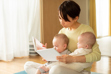 絵本を読む母親と双子の赤ちゃん