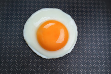 Fried egg in a pan. Black background. Top view                                                
