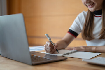 Young asian woman writing notes in notebook watching webinar video course, serious black male student looking at laptop listening lecture study online on computer e learning