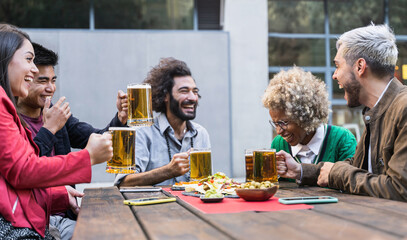 Happy friends drinking beer in outdoors bar having fun and laughing telling hilarious joke