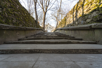 Fototapeta na wymiar old concrete stairs towards the top along the edges of the stone walls with moss