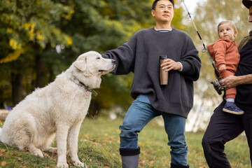 Multiracial male friends talking and having fun at picnic in nature at autumn. Concept of leisure, weekend and entertaiment. Idea of male friendship. Asian guy care his dog