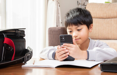 勉強中にスマホを見る小学生の男子