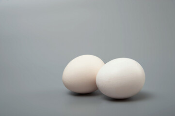 Two white eggs on a gray background. Minimalism. Healthy food concept. 