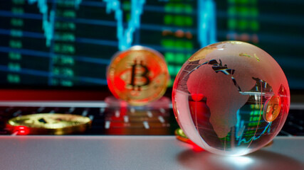 Gold coins and crystal earth globe with bitcoin symbol collaged, on computer, in front of graphic image. Focus on crystal earth globe.