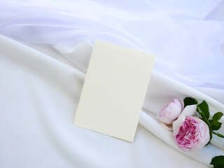 Top view mockup blank card, for greeting, wedding invitation template with rose flower on white cloth background. with clipping path