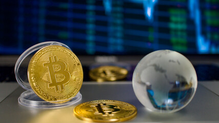 Gold coins and crystal earth globe with bitcoin symbol collaged, on computer, in front of graphic image. Focus on bitcoin money.