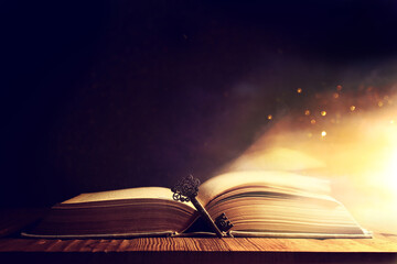 image of open antique book on wooden table with vintage key