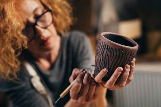 close up of woman carving clay pot in her workshop