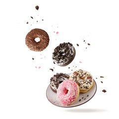 Colorful glazed donuts with mixed sprinkles and crumbs flying isolated on white background.