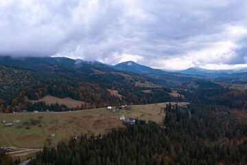Fototapeta premium Aerial view of beautiful forest and mountain village on autumn day