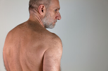 Rear view of shirtless muscular mature man against white background