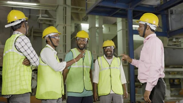 group of industrial workers having fun chat with manager or supervisor at factory - concpet teamwork, collaboration and communication
