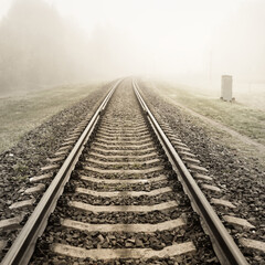 Railroad track in a thick white fog, forest in the background. Concept landscape. Freight and...