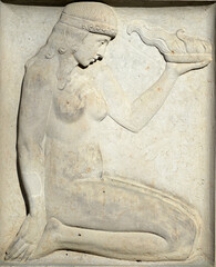 An old sandstone relief which shows a naked woman with a fire bowl in her hand.
