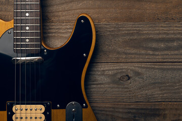 Vintage black and yellow electric guitar on wooden background