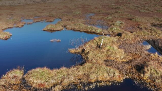Aerial view of the swampy wetlands in northern Norway. Blue sky reflected in the mirrorlike lakes. Slow-motion.