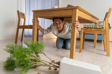 地震・災害で机に隠れる男性