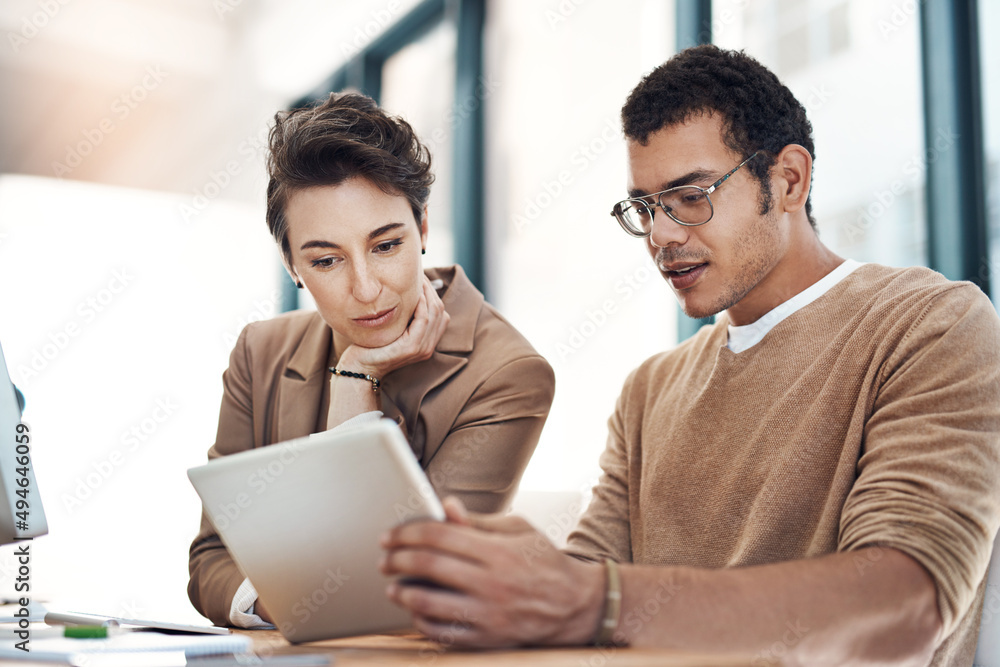 Poster the online world holds all the answers. shot of two businesspeople working together on a digital tab