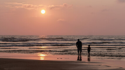 Sunset on the beach, silhouette of a father and his son/Coucher du soleil sur la plage, silhouette d'un père et son fils