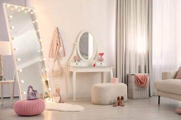 Large mirror with light bulbs and dressing table in stylish room. Interior design