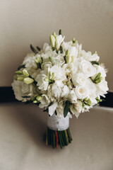 Wedding rings of the bride and groom lie on a bouquet of white flowers and greenery