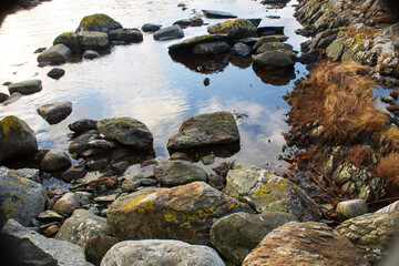 A close view of stone on the beach in the Norway at the cliff in calm water.Autumn. Travel. Skudeneshavn.