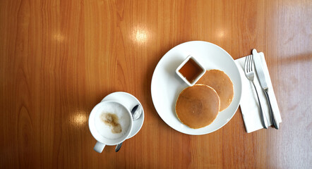 Two pieces of pancakes served with maple syrup on wooden table. Top view.