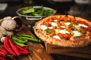 Wood fired artisanal pizza cooked in wood oven on rustic vintage chopping board served with fresh...