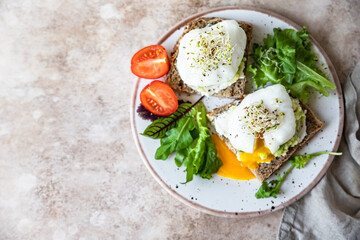 Sourdough bread with cream cheese, mashed avocado and poached egg served with salad leaves, tomatoes and sprouts. Healthy breakfast or brunch. Diet food concept.