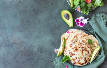 Homemade chapati or roti flatbread with green salad mix, avocado and sprouts. Freshly baked Indian flatbread. Top view.