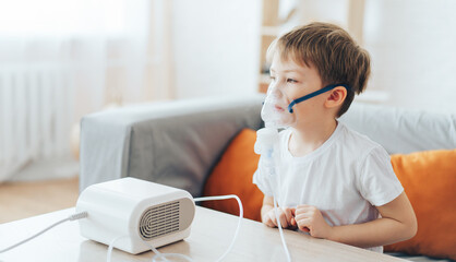 Little boy wearing nebulizer mask breathes allergy medicine.
