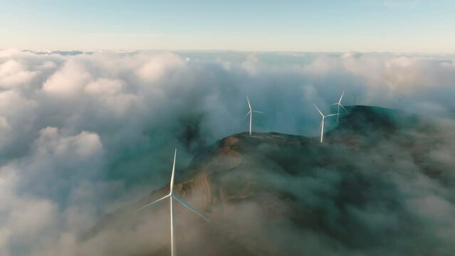 Wind turbines produce electricity in the mountains. Wind turbines hidden in the morning fog.