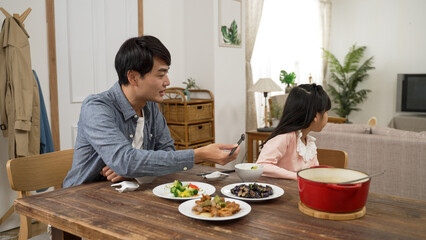 upset asian daughter turning head and refusing to eat while her father is feeding her vegetable...