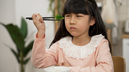 closeup of unhappy Asian girl complaining with a disgust expression while looking at green...