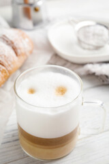 Obraz na płótnie Canvas Delicious latte macchiato and croissant on white wooden table