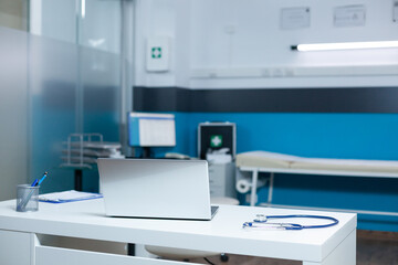 Medical professional workspace with doctor office desk having modern laptop, diagnostic equipment...