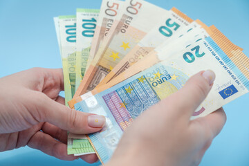 Woman's hands holding stack of money (euro) on blue background. Money. Business