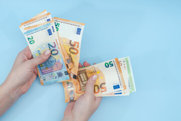 Female hands counting stack of euro banknotes on blue background. Money. Business. Finance