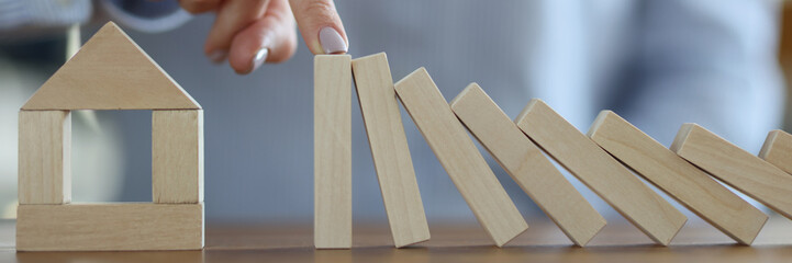Business woman stoping falling wooden blocks in front of house closeup