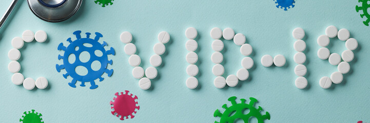 Covid19 word laid out from white pills on blue background closeup